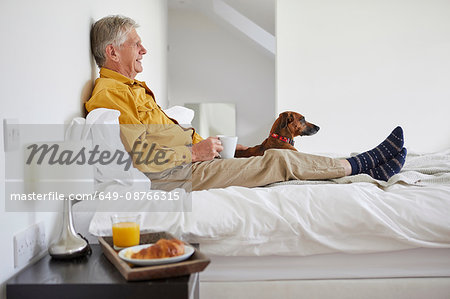 Dog enjoying breakfast in bed with owner