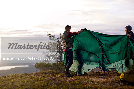 Hikers setting up tent on hilltop, Keimiotunturi, Lapland, Finland