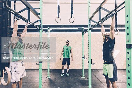 Two male cross trainers training on exercise bar in gym