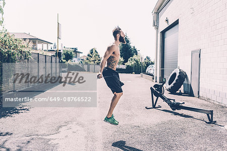 Young male cross trainer skipping outside gym