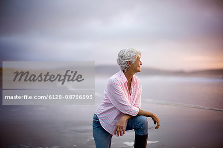 Elderly woman watching the sunset at the beach.