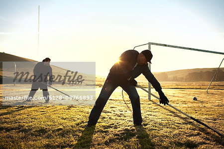 Groundskeepers raking a soccer field.