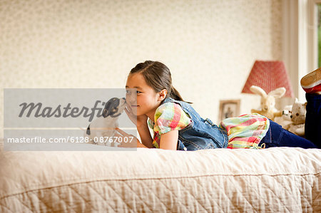 Portrait of young girl on her bed with a cute puppy.