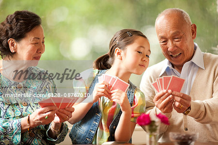 Senior couple playing cards with their granddaughter.