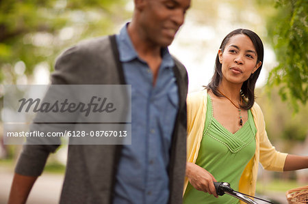 Couple walking down a residential street with a bicycle.