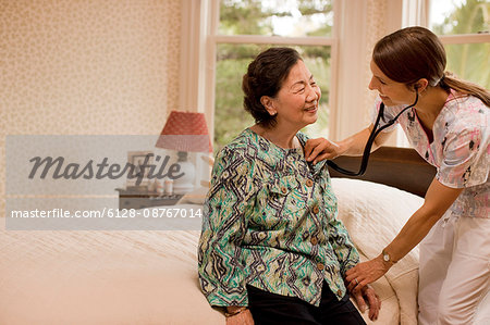 Nurse listening to the heartbeat of a senior woman at home.