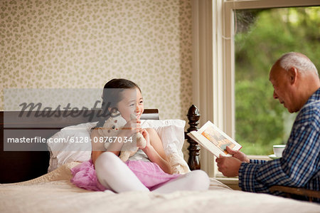 Senior man reading a story with his granddaughter.