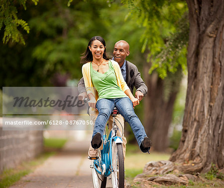 Young couple playfully riding a bicycle.
