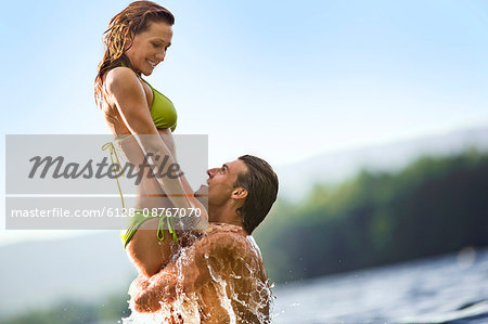 Couple in a lake,  man preparing to throw woman in the air.