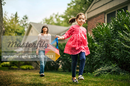 Young girl skipping while her mother watches.