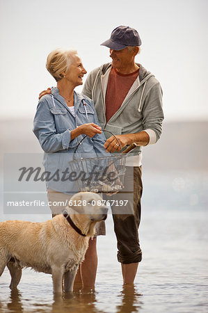Smiling senior couple wading on a beach at low tide.
