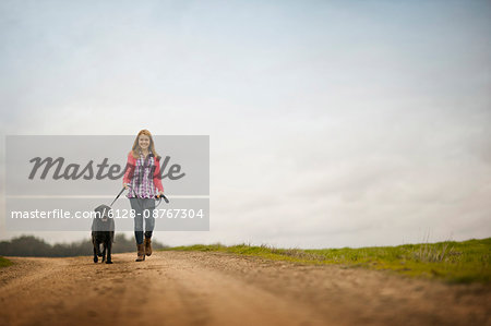 Portrait of a happy teenage girl walking her dog along a dirt road.