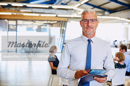 Portrait confident businessman with digital tablet in office
