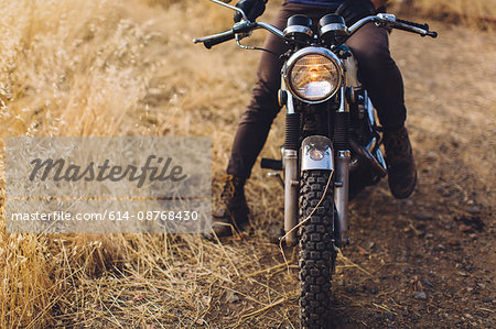 Man sitting on motorbike, low section