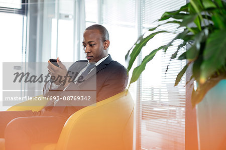 Young businessman using mobile phone on chair in office