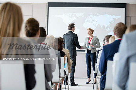 Business people shaking hands during seminar at convention center