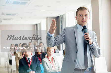 Businessman speaking through microphone during seminar in convention center