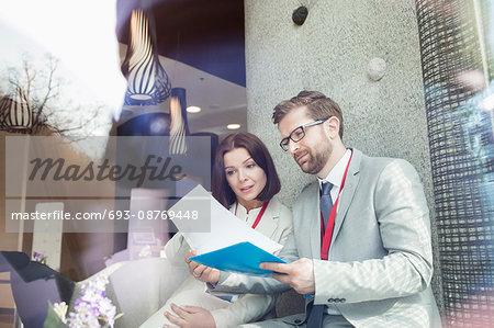 Business people reading document while sitting in convention center