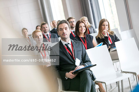 Businessman looking at public speaker during seminar in convention center