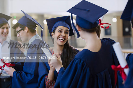 Happy female college student graduates with cap and gown and diplomas celebrating