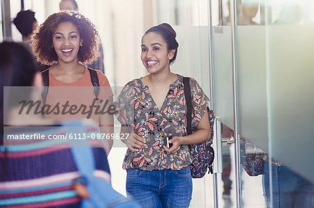 Smiling female college students walking in corridor