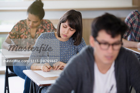 Female college student taking test at desk in classroom