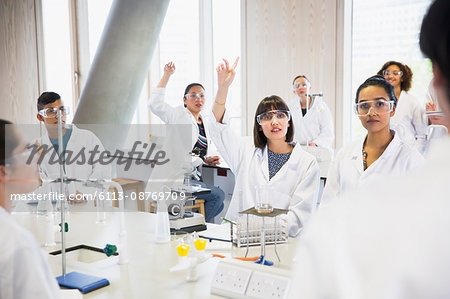 College students raising hands in science laboratory classroom