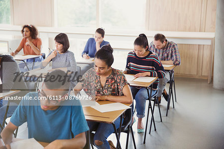 College students taking test at desks in classroom