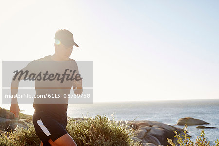 Male triathlete runner running along ocean