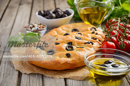 Italian Focaccia bread with olives and rosemary on rustic wooden background, selective focus, copy space