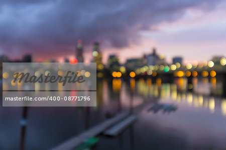 Portland Oregon city downtown waterfront skyline along Willamette River after sunset at dusk out of focus blurred bokeh lights