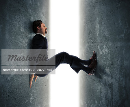Businessman man trapped between two walls strives to push