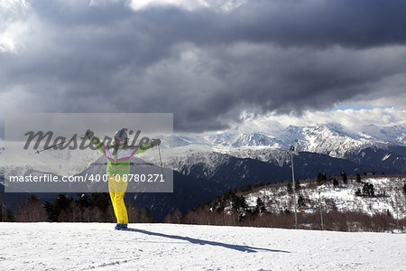 Happy young skier with ski poles in sun mountains and cloudy gray sky. Caucasus Mountains. Hatsvali, Svaneti region of Georgia.