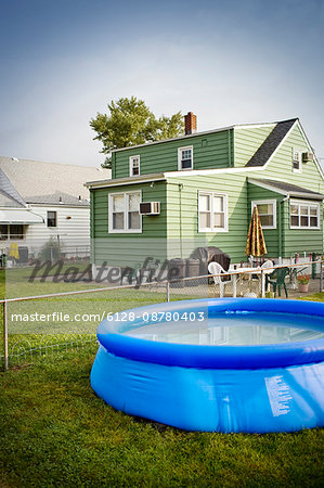 Blow up paddling pool in the back yard of a house.