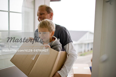Father carrying son in box while moving house