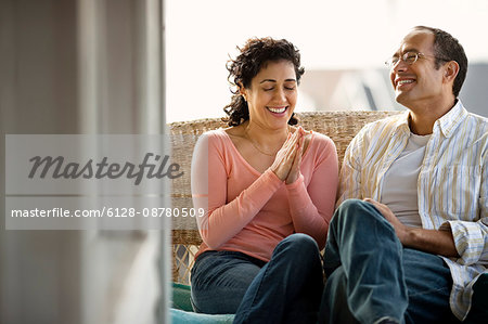 Happy mid adult couple sitting on a front porch.