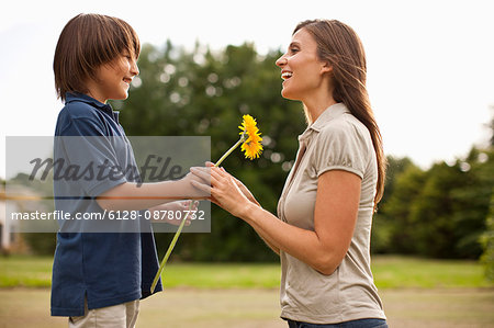Young boy giving his mother a sunflower.