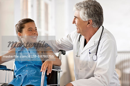 Young girl in a wheelchair talking to her doctor.