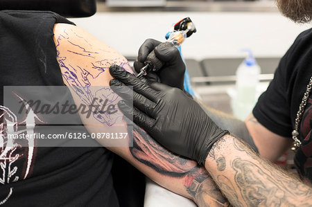 Sweden, Tattoo artist working on arm tattoo