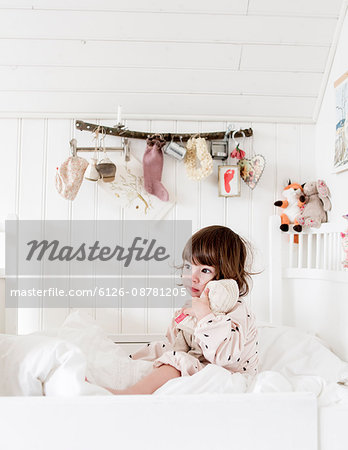 Sweden, Small girl (2-3) sitting in bed and embracing doll