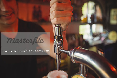 Close-up of bar tender filling beer from bar pump at bar counter