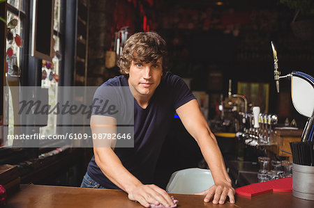 Portrait of bar tender cleaning bar counter at bar