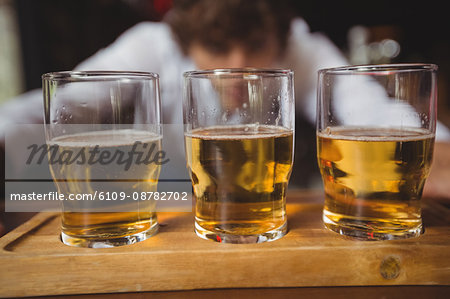 Bartender lining whisky shot glasses on bar counter at bar
