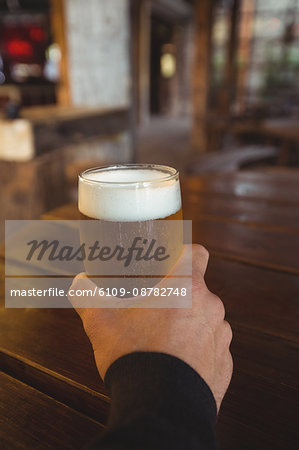 Man holding glass of beer at bar