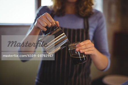 Mid section of waitress preparing coffee at counter in workshop