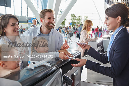 Customer service representative helping family checking in with tickets at airport check-in counter