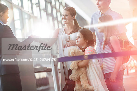 Flight attendant checking tickets of family in airport