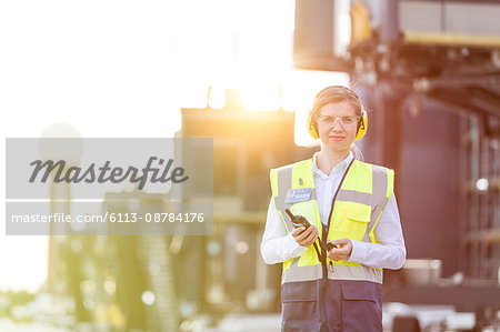 Portrait confident female air traffic controller with walkie-talkie on airport tarmac Portrait confident female air traffic controller with walkie-talkie on airport tarmac