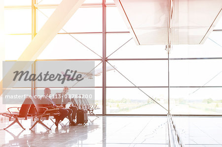 Businessmen talking and working at laptop in airport departure area