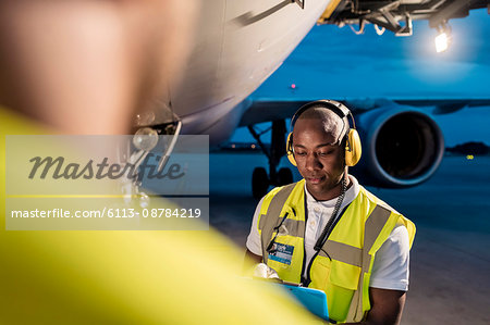 Air traffic control ground crew working under airplane on airport tarmac